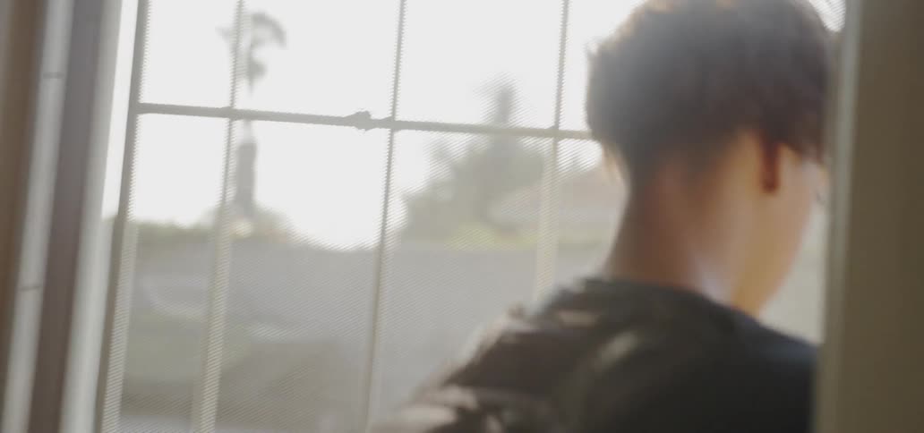 A teenager walks through a front door