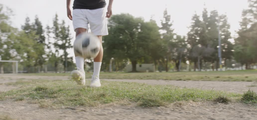 Teenager kicks a soccer ball in an outdoor field