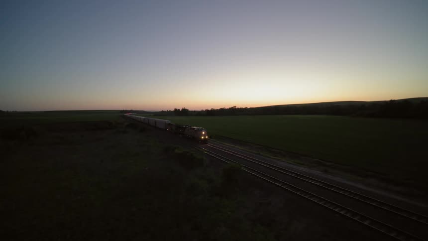 Night time converge of a massive freight train rolling thru farm country