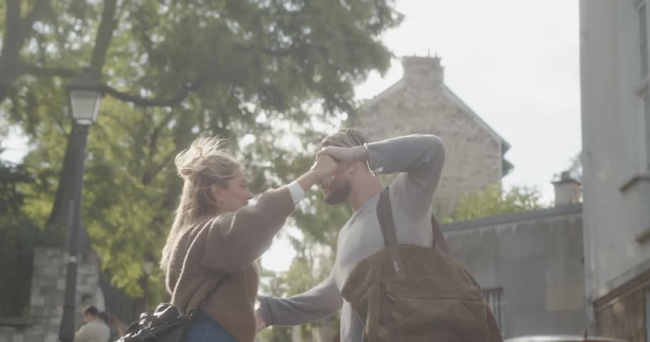 A man and woman dance on a sidewalk