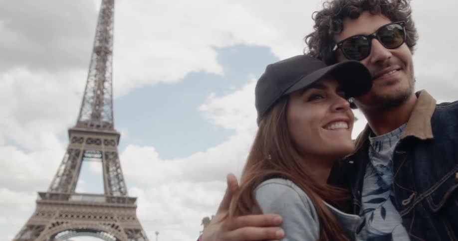 Man and woman kiss as the man takes a self photo with his cellphone