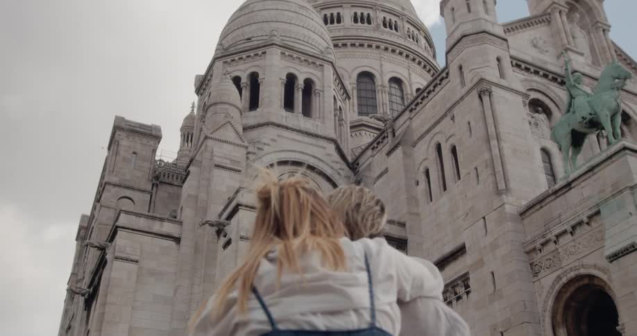 A man and woman hug while looking at a large stone building