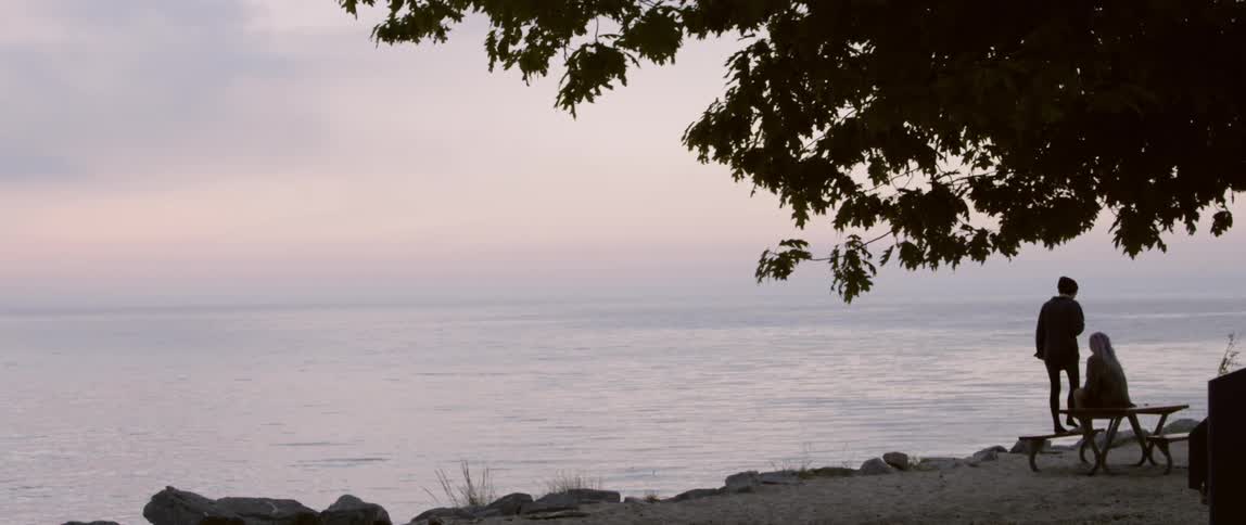 A person looks over the cliff onto the water