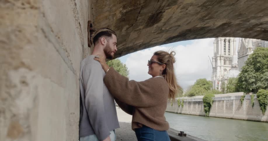 Couple kisses under bridge near notre dame cathedral