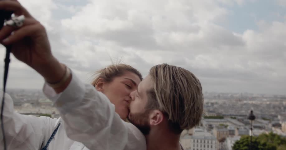 Woman takes selfie as she kisses her boyfriend