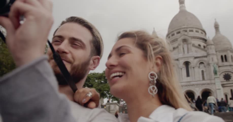 Man holds a camera as he and a woman look at its screen