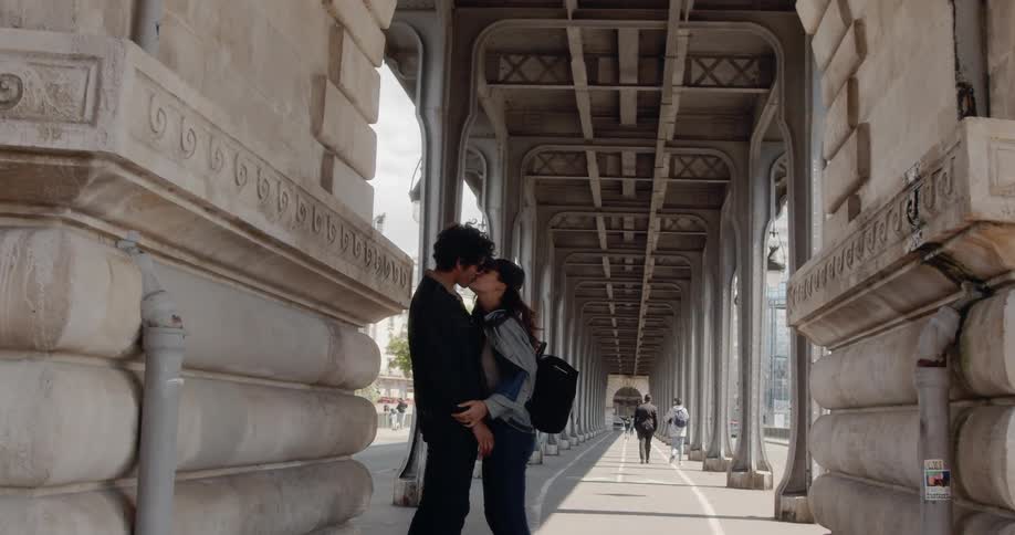 A young married couple kiss on Pont de Bir-Hakeim in Paris