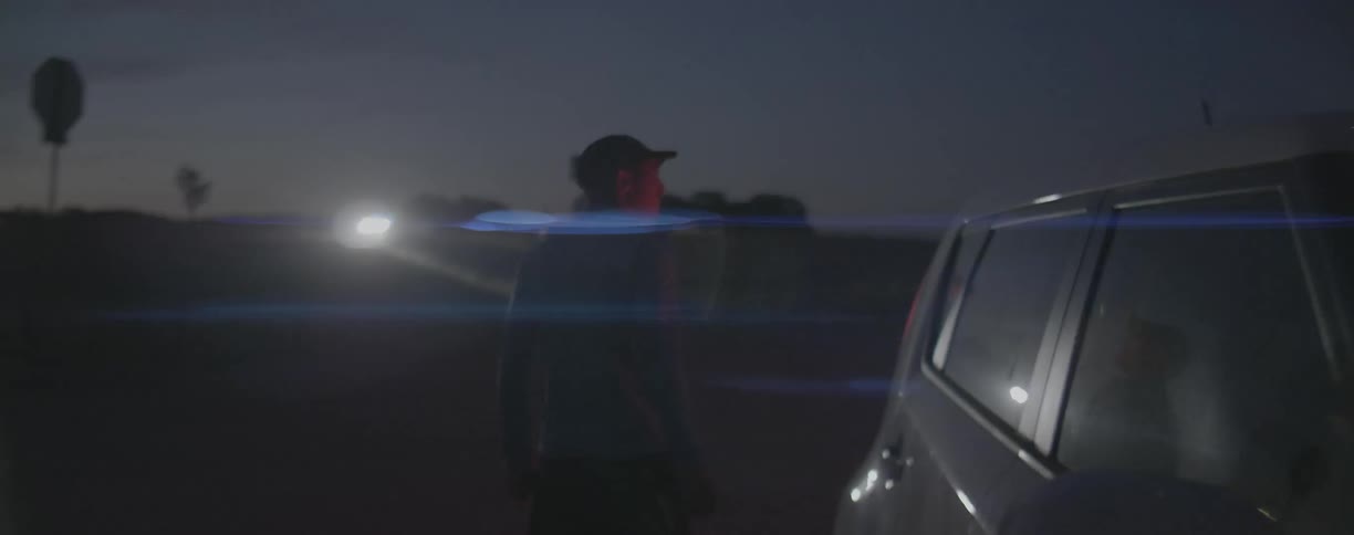 Man walks behind a vehicle in the dark