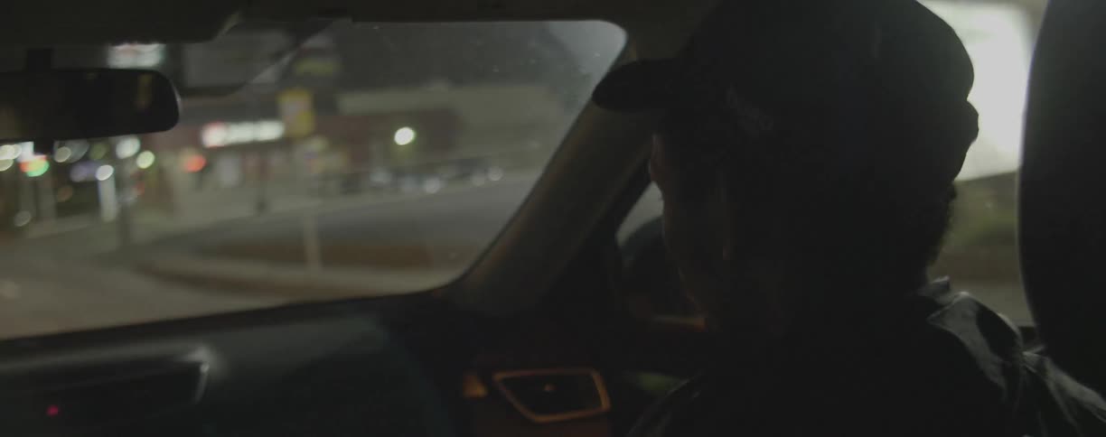Man sits in a car as it travels down the city street at night