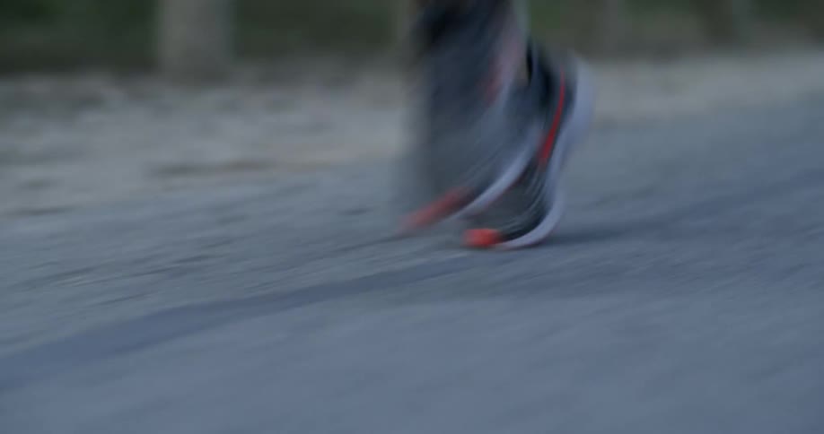 A man's sneakered feet hit the pavement as he runs