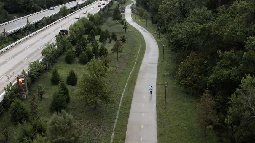 A runner jogs on a path next to a highway