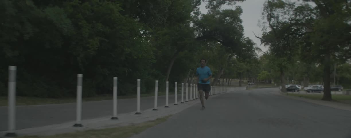 Man jogs in park near highway
