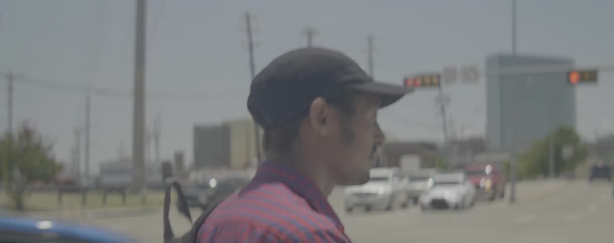 Man with backpack walks along urban street