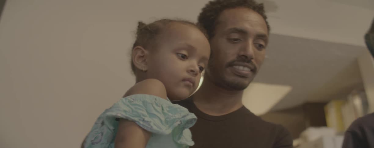 Man smiles as he holds a young toddler