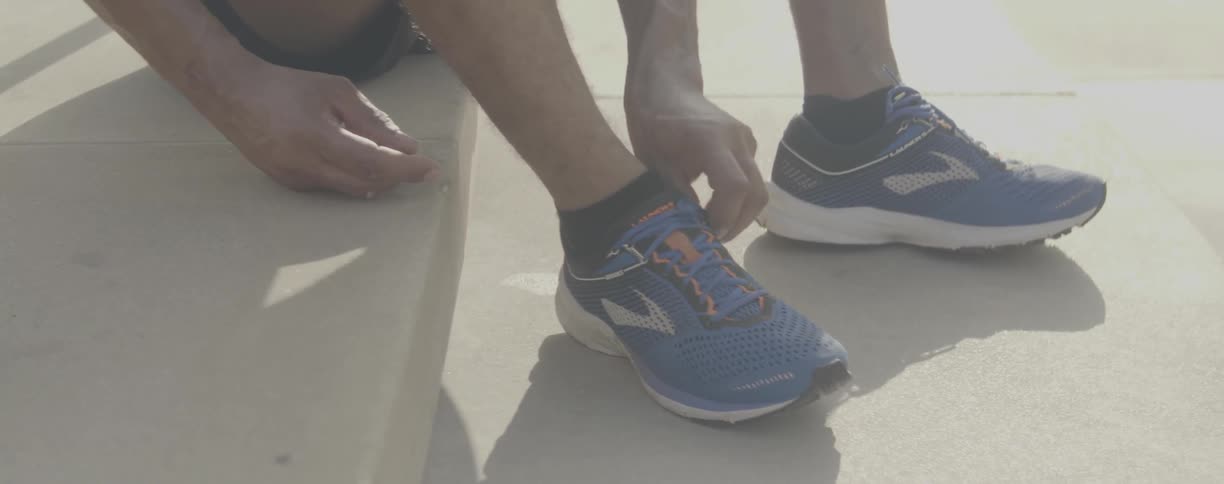 Man sits on a step as he adjusts his shoes
