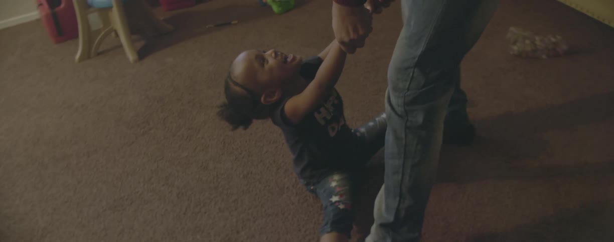 A man is playing with his daughter in their living room in daylight