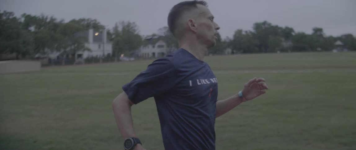 Man is sprinting on running track at dusk