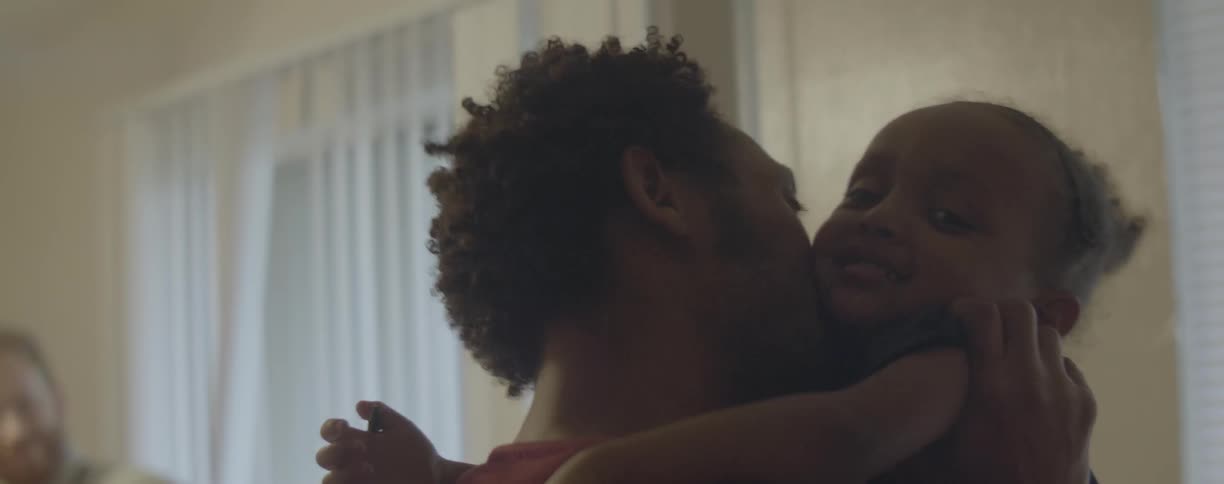 A father kisses and holds his young daughter