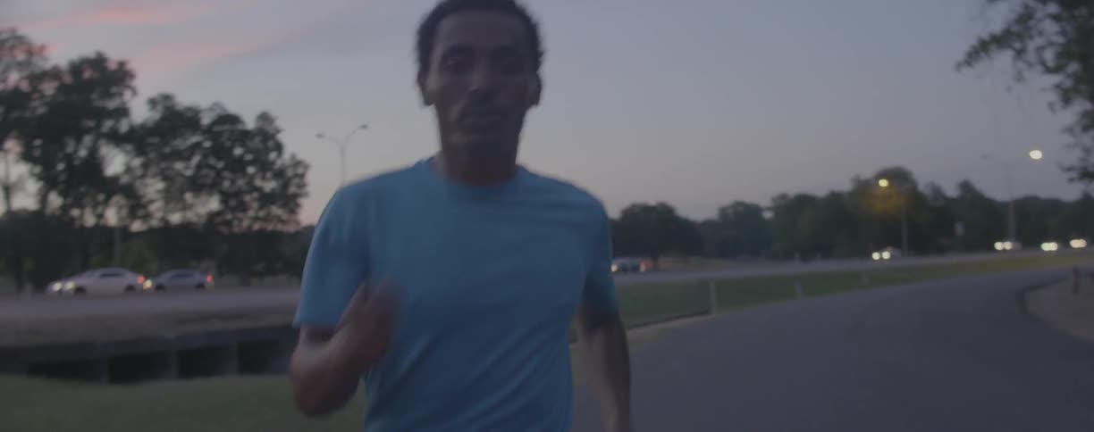 Man runs down a road next to a busy highway