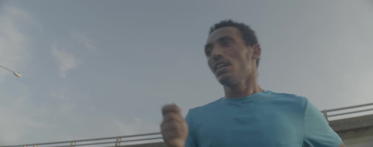 A man jogs beneath a city bridge
