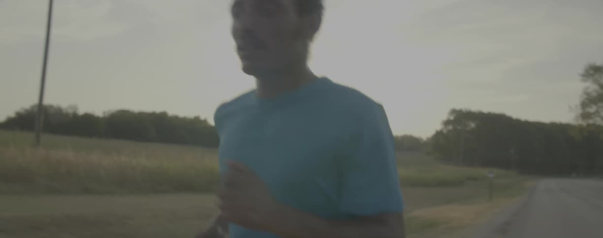 Man runs near a field on a sunny day
