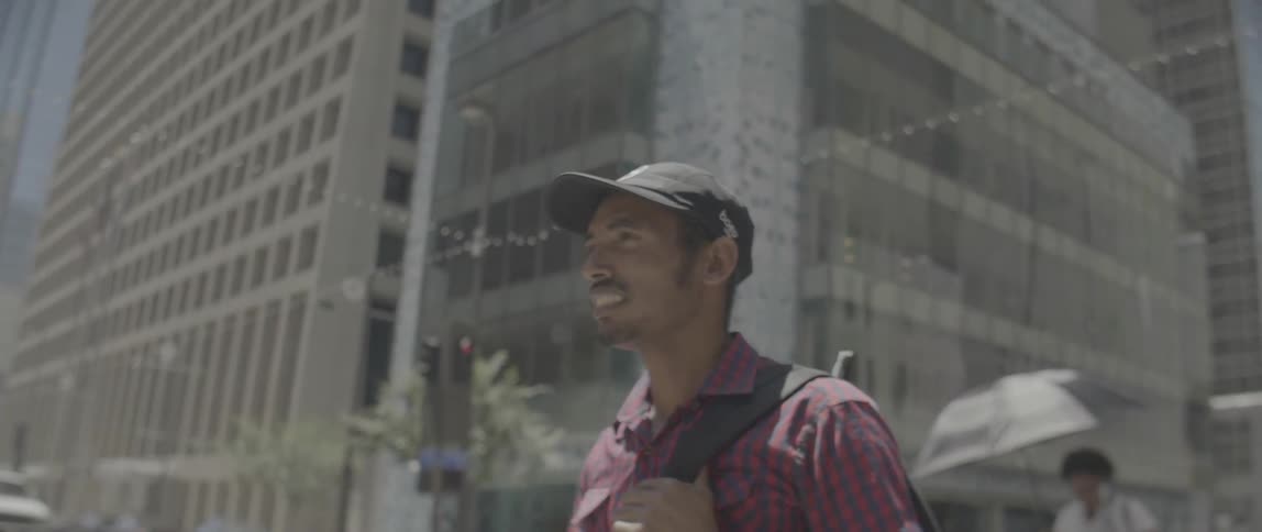 Man is smiling while walking in city on sunny day