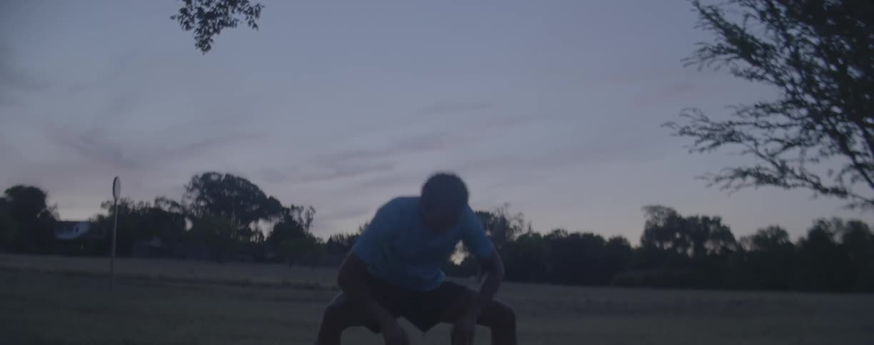 Man does lunges as he stretches in a field
