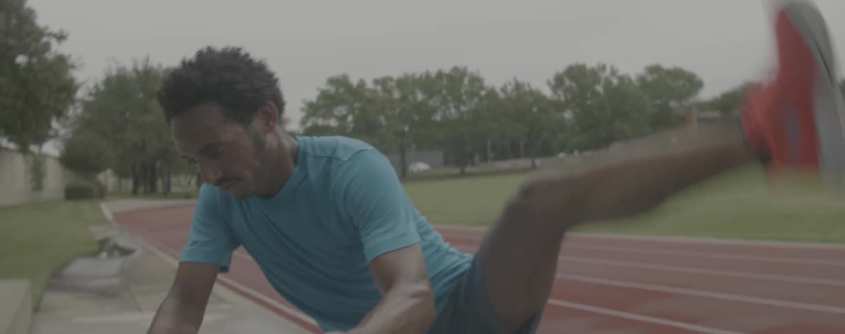Runner is stretching his legs on the track