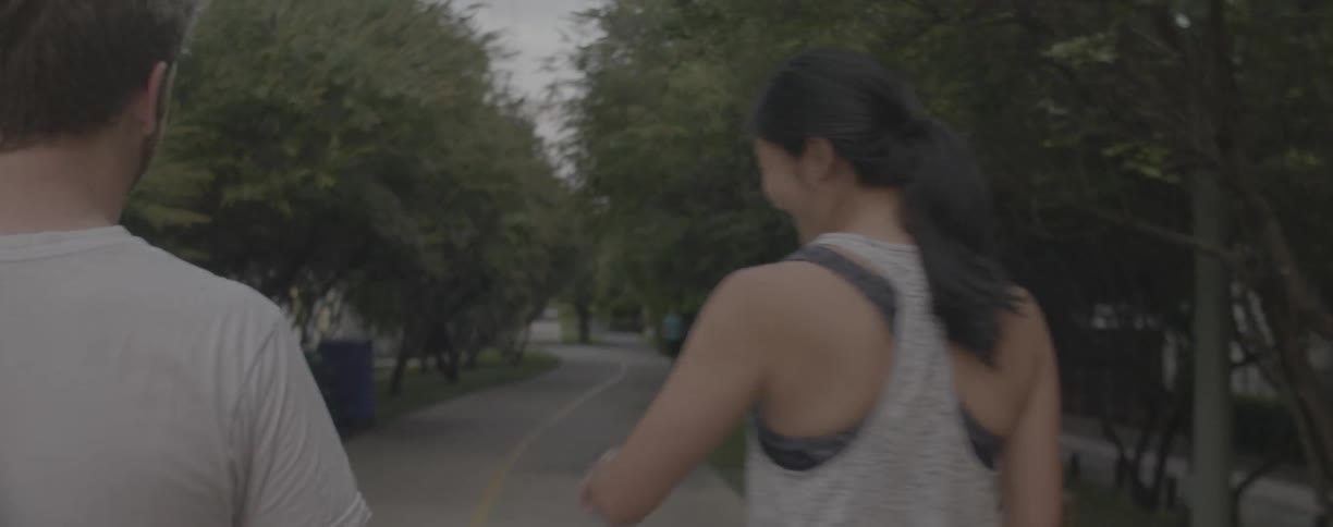A man and woman laugh as they get ready to jog on a trail