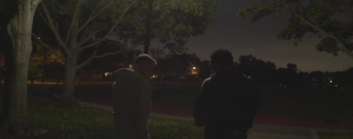 Men walk on a sidewalk at night
