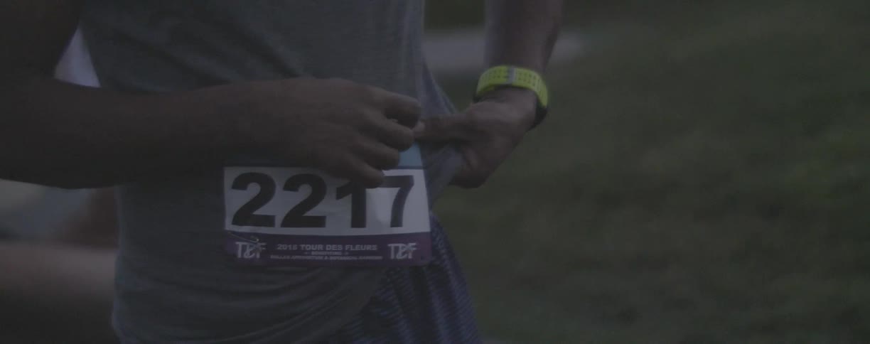Man wearing a race tag adjusts his shirt