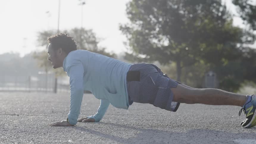 A man does push ups outside on a sunny day