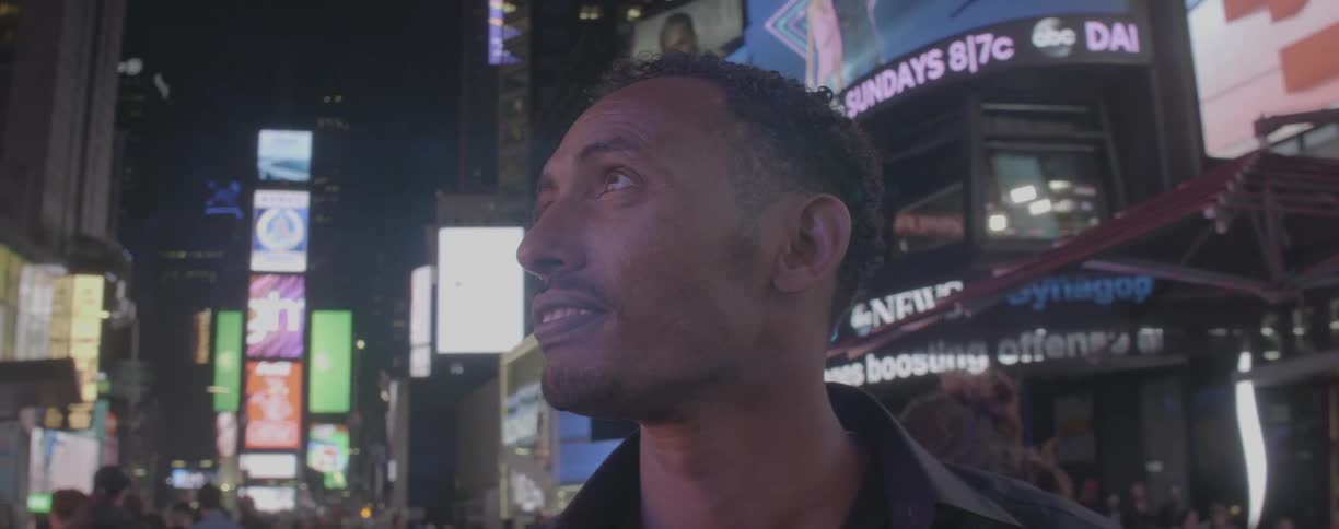 Man stands in a city as he looks around at the stores