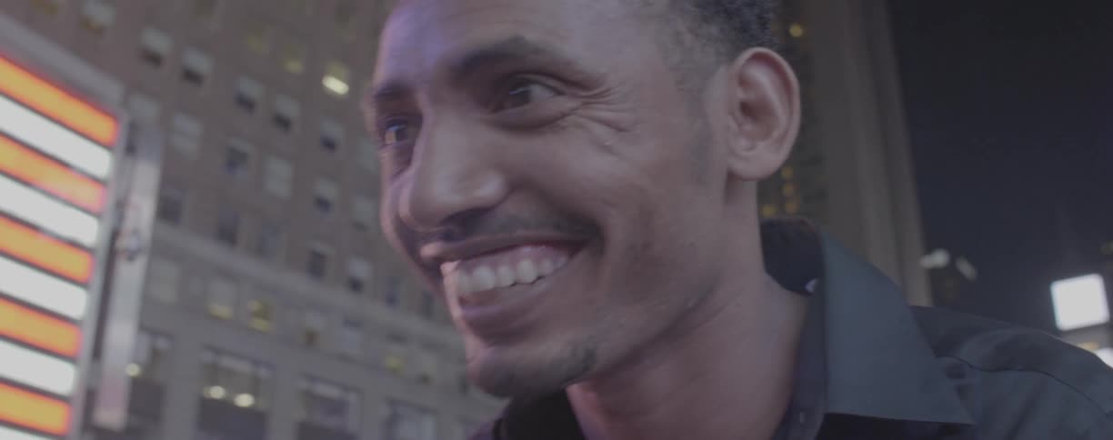A man smiles and laughs in a city at night