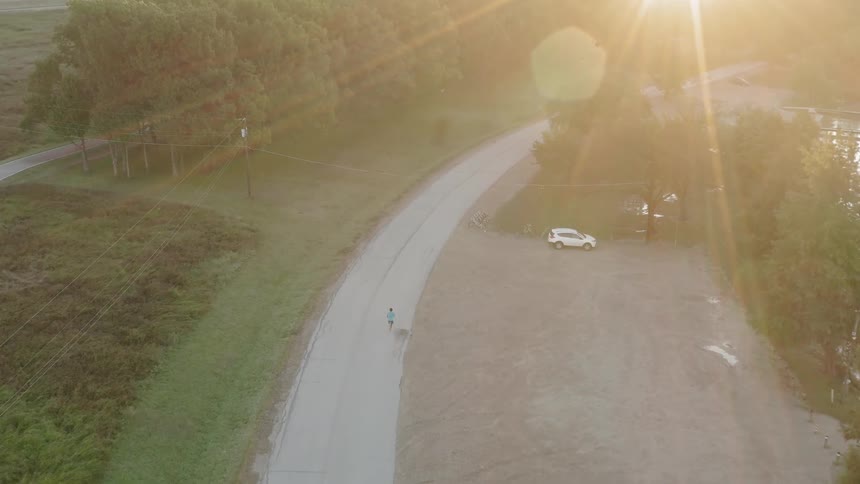 A runner jogs on a rural road at sunset