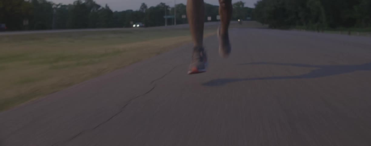 A runner jogs on a paved path at dusk