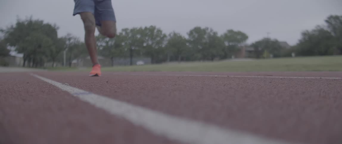 A man runs on an outdoor racetrack