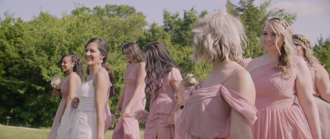 Bride and bridesmaids walk near the trees