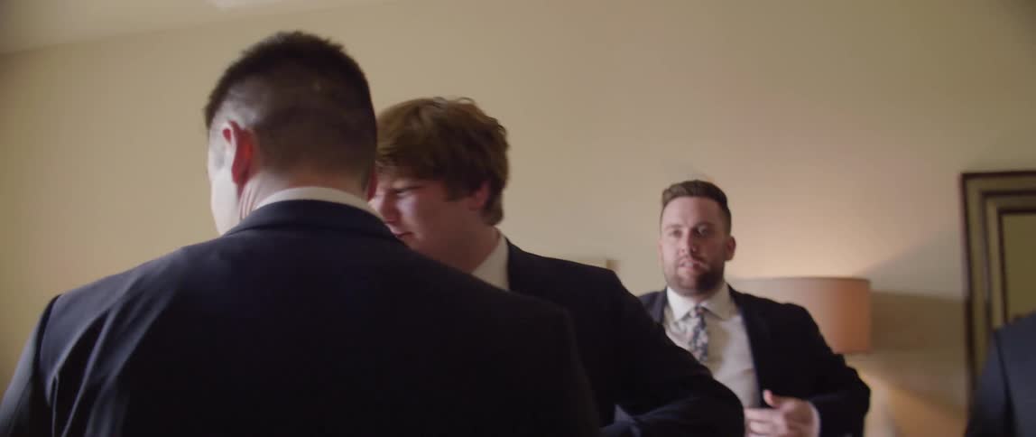 A groom and groomsmen get ready in a dressing room