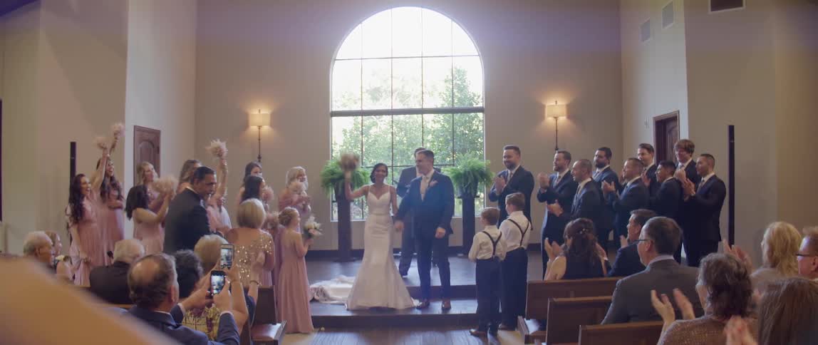 Weddings guests applaud for newlyweds at their ceremony