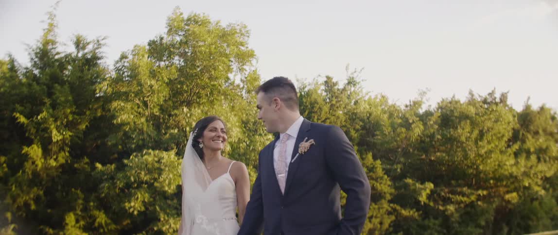 Bride and groom are smiling and holding hands while walking outside