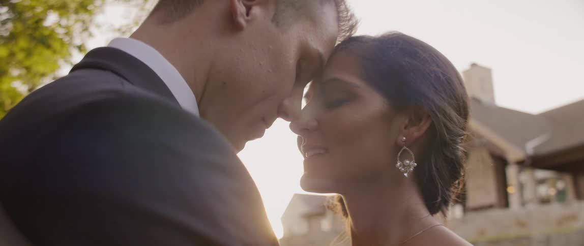 A bride and groom nuzzle outside at sunset