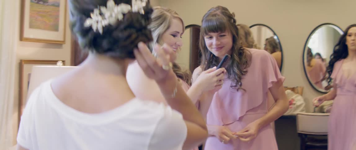 Woman adjusts her hair as another woman texts on her cellphone