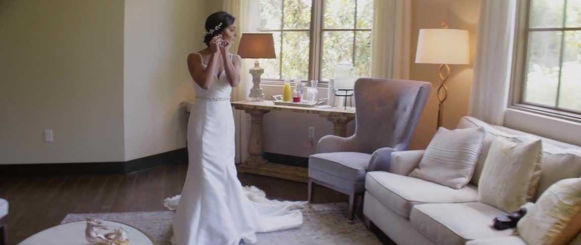 Woman in a wedding dress adjusts her earrings