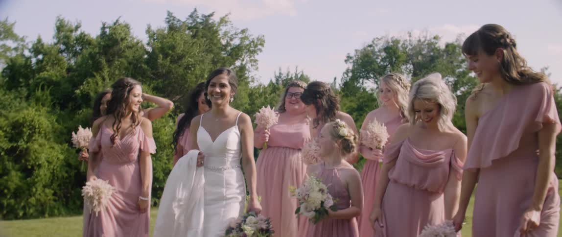 A bride and bridal party smile while walking outside