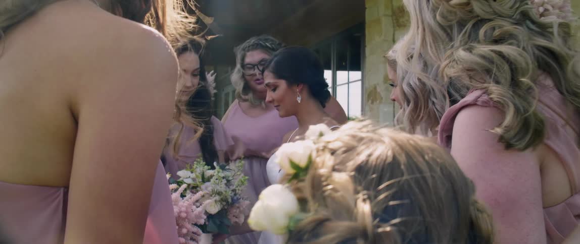 A bride stands with her bridesmaids outside