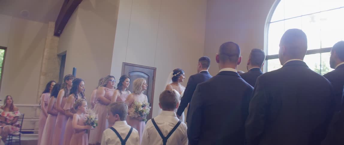 A bride and groom hold hands during their ceremony as their attendants look on