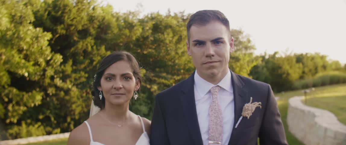 Bride and groom stand together near the trees