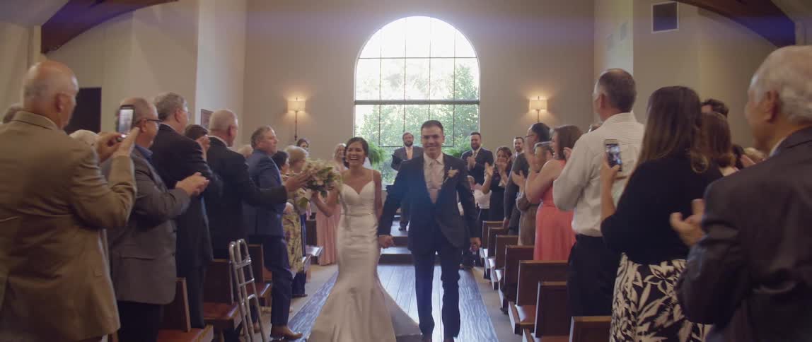 Guests are clapping as bride and groom walk down aisle after being married