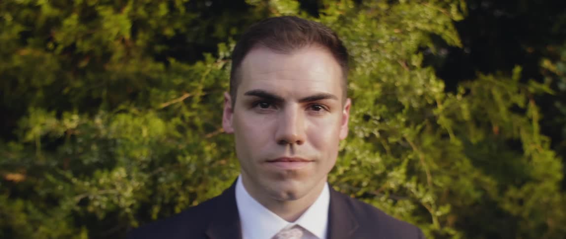 Man in suit is standing outside and staring off on sunny day